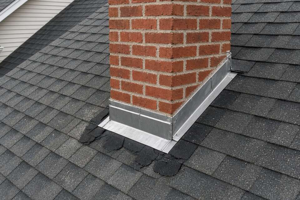 Metal flashing around a brick chimney on a shingle roof
