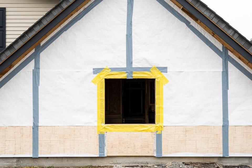Gable wall wrapped in housewrap with taped seams and flashing tape around a window opening
